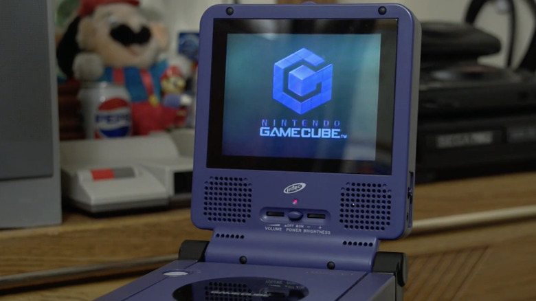 a Nintendo GameCube next to a controller sitting on a table not playing on a TV