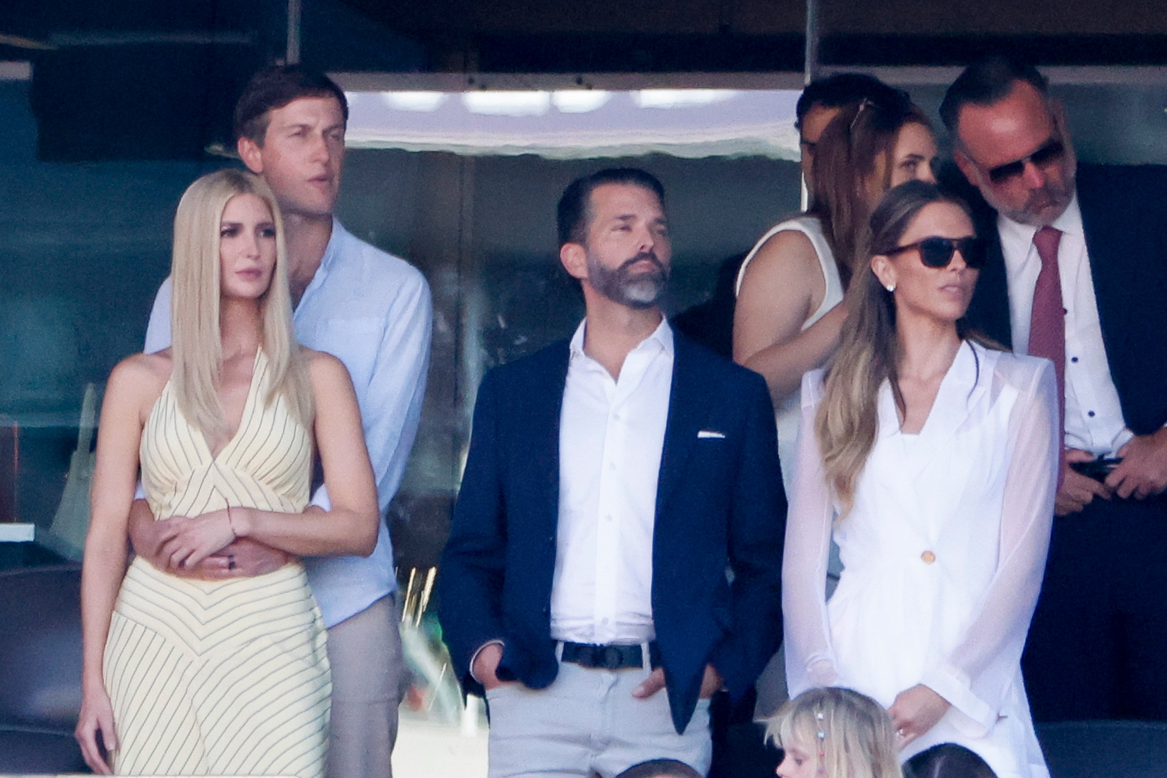 Several people are gathered at an event, some wearing business-casual attire, watching attentively