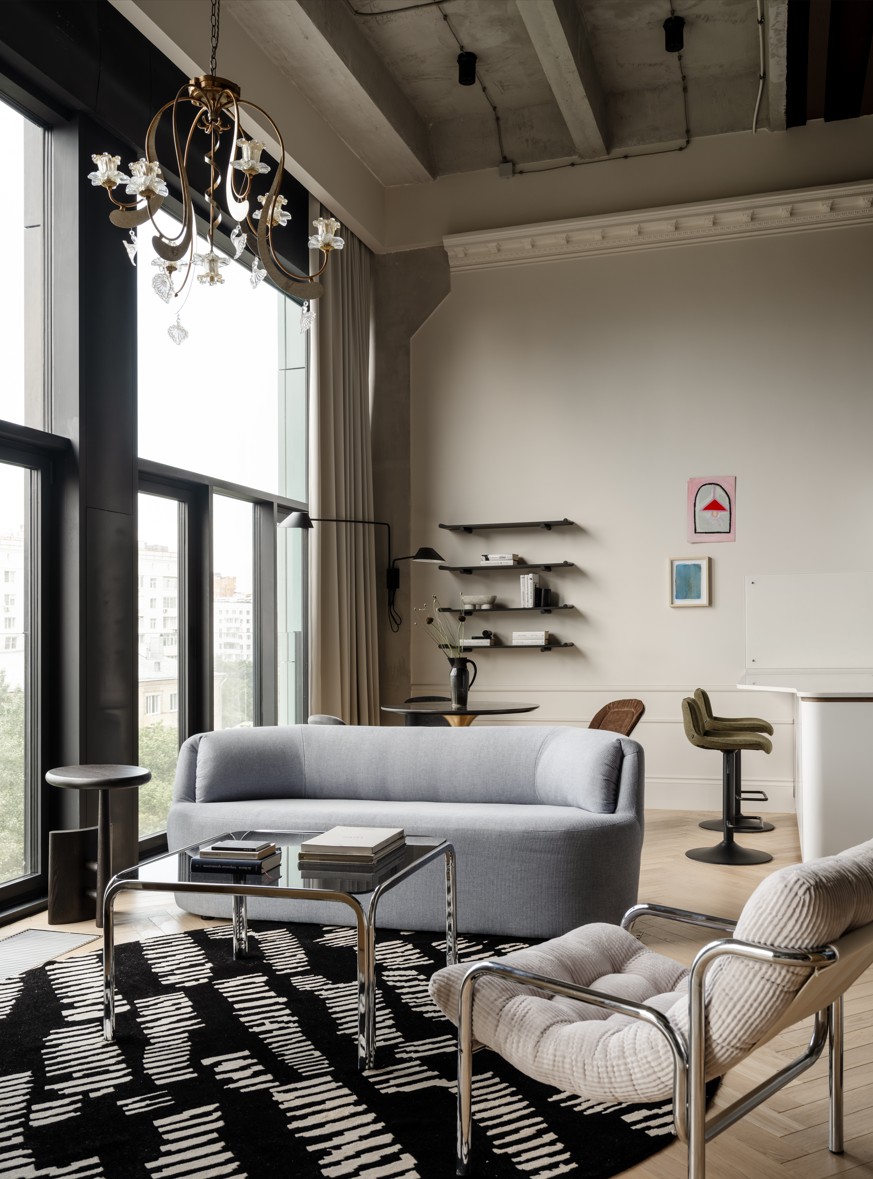 A curved grey sofa and a mid-century chair in a living room