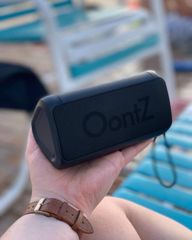 reviewer holding a black triangle-shaped Bluetooth speaker