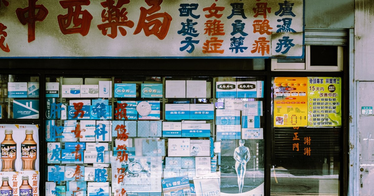 A traditional storefront with Asian script and various posters displayed in the window.
