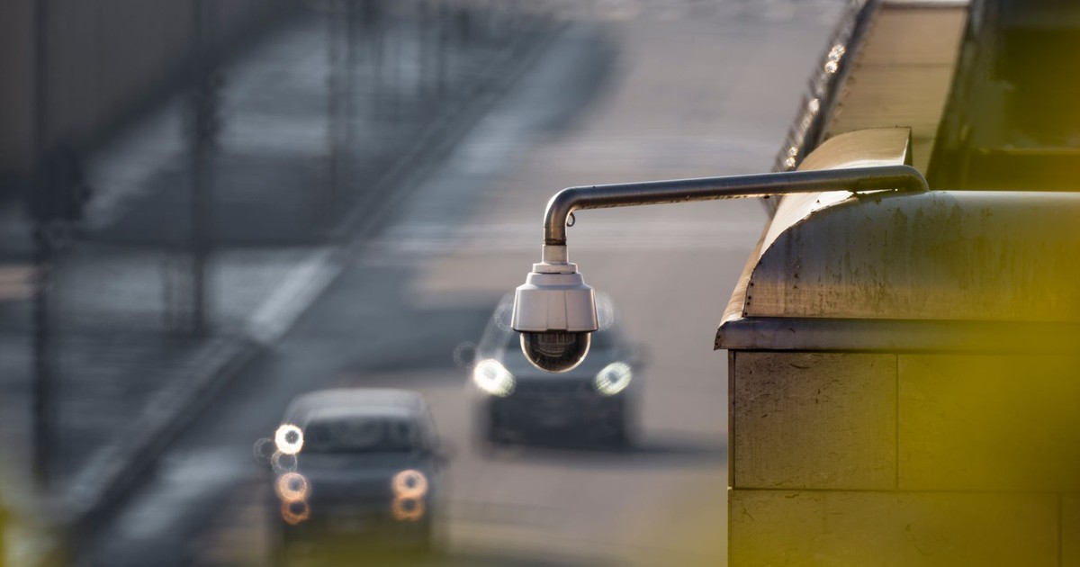 CCTV camera overlooking a busy street with cars in motion, capturing urban surveillance.