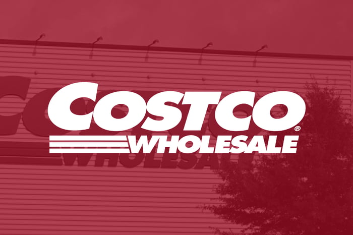 Costco logo on red filter with signage in background.