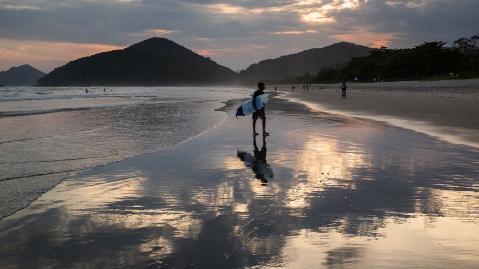 A surfer walks along Itamambuca beach at sunset. It's known for some of the most consistent waves on Brazil’s nearly 5,000 miles of coastline. - Alex Saberi/Photodisc/Getty Images