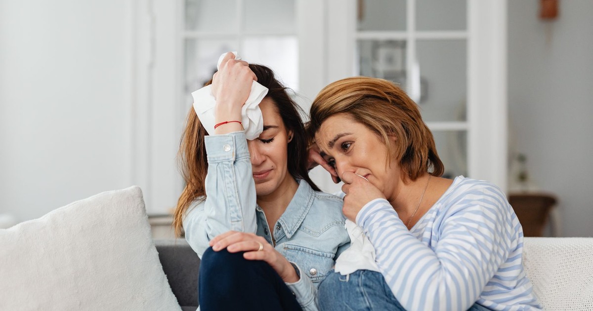 Two women sitting on a sofa, comforting each other in a moment of shared emotions.