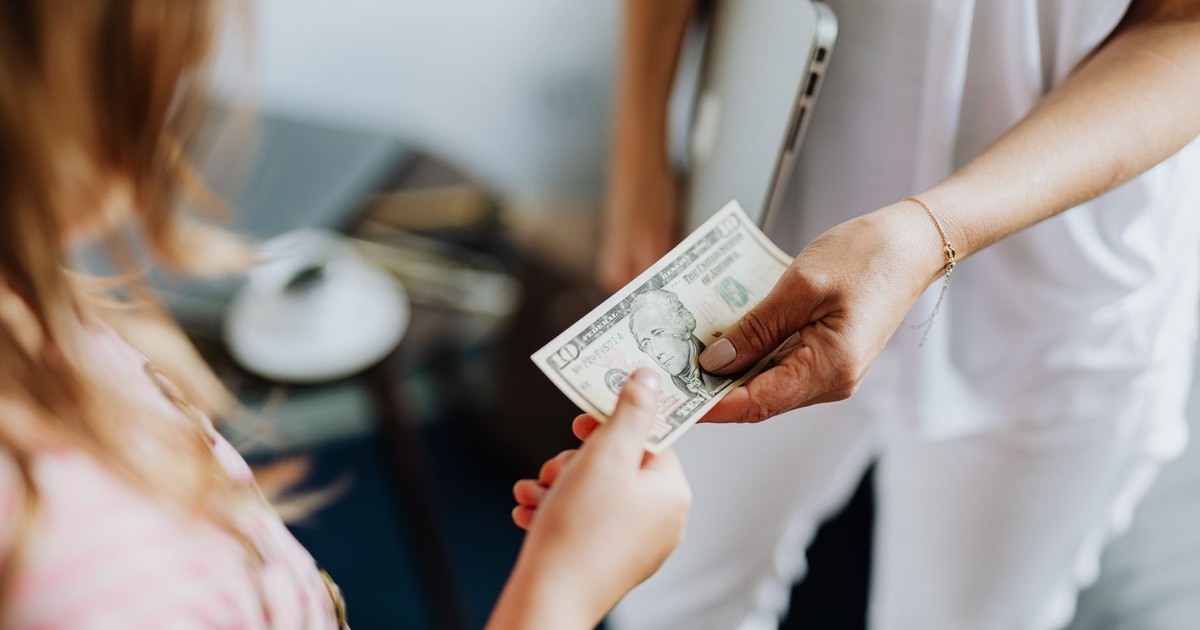 Close-up of a transaction involving a US dollar bill exchanged indoors between two individuals.
