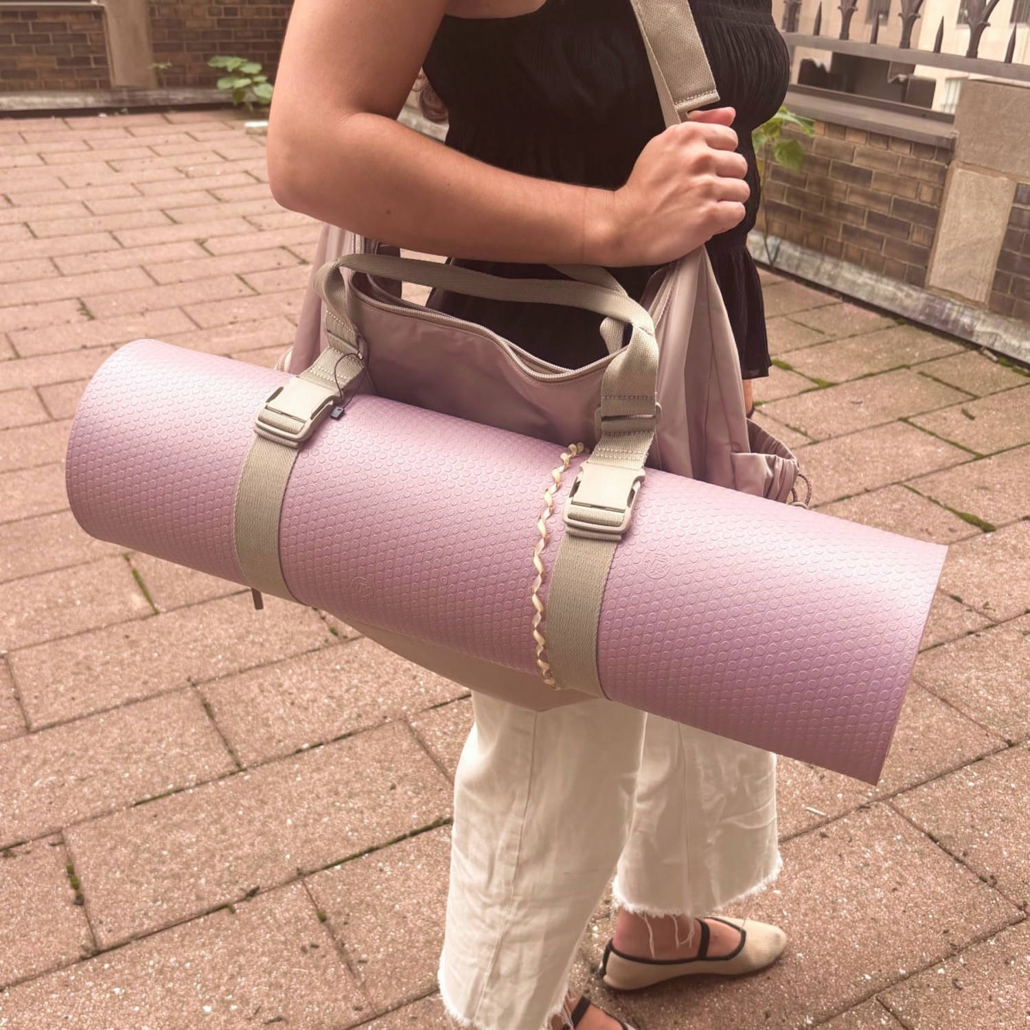 Woman holding Calpak gym duffel with a rolled up yoga mat attached to it. (Daaiyah James / NBC News)