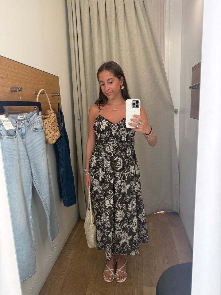 Person taking a selfie in a fitting room wearing a floral dress