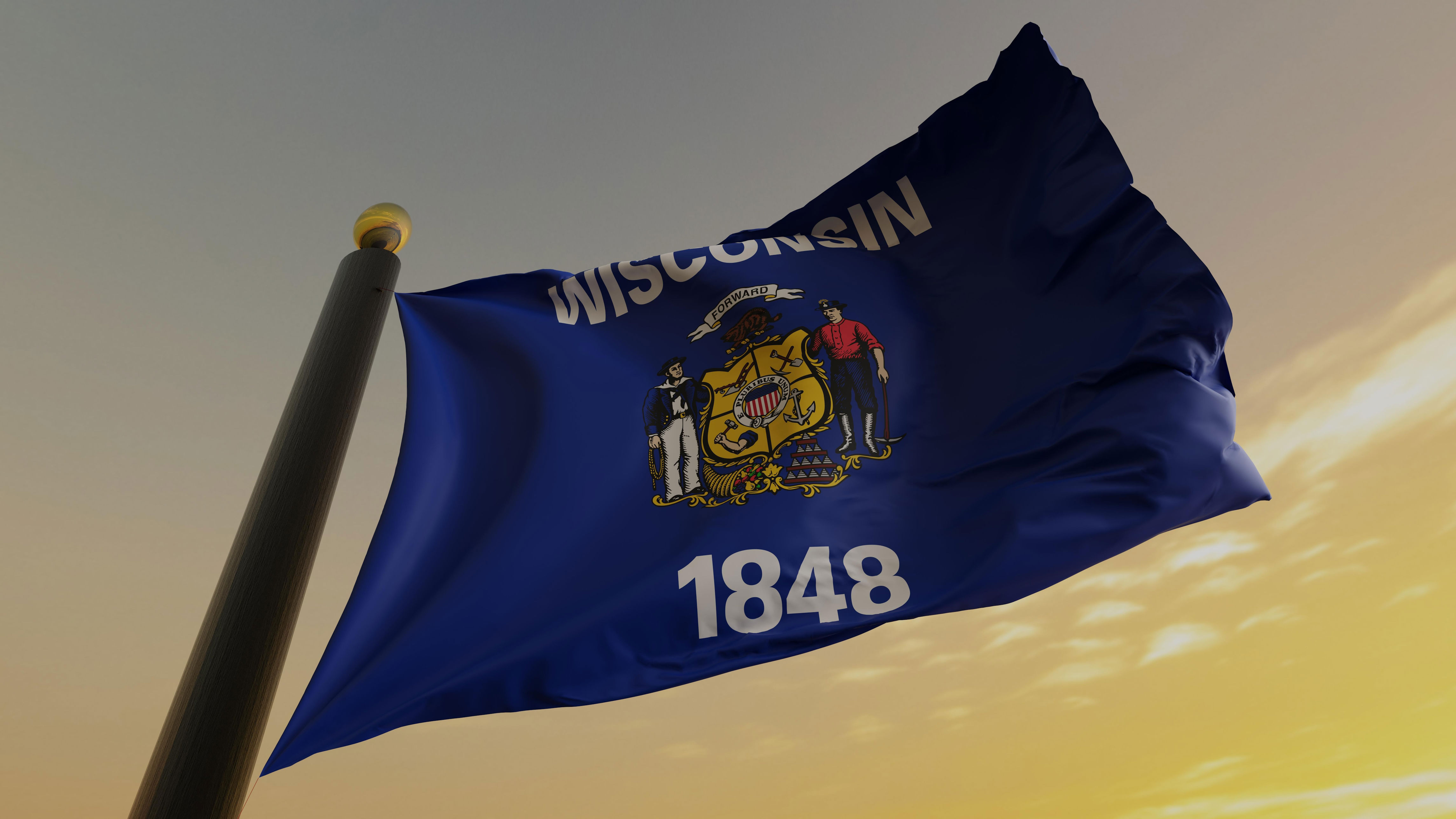 A Wisconsin state flag flys in the forground in front of a yellow sky in the background