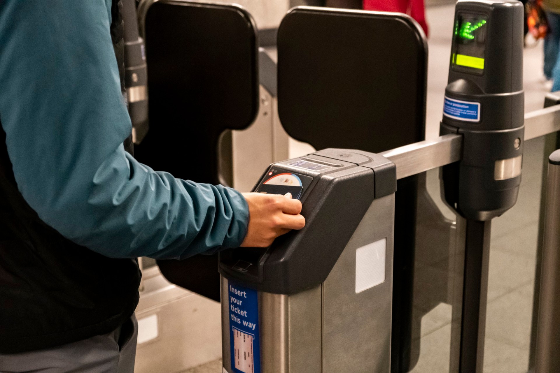 A man puts his card on the ticket barrier at the station