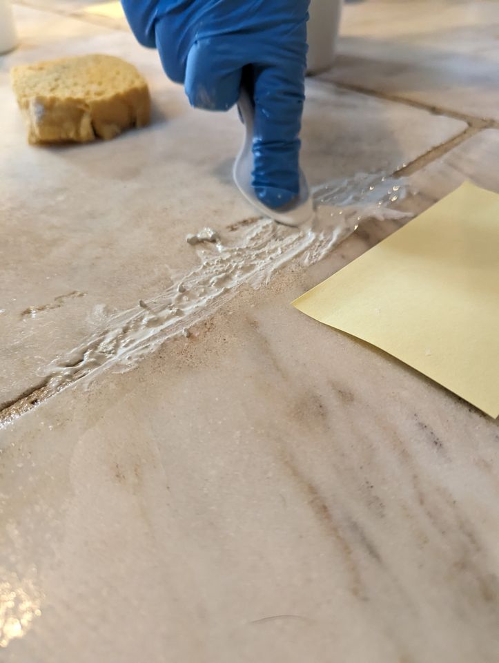 Filling grout with a spoon.