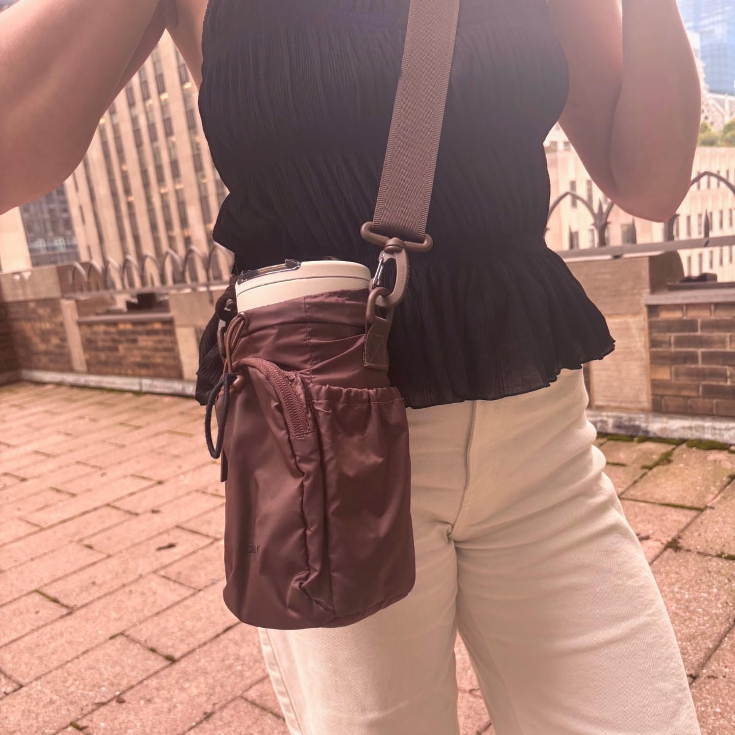 Woman wearing Calpak brown Water Bottle Holder outside. (Courtesy Cory Fernandez)