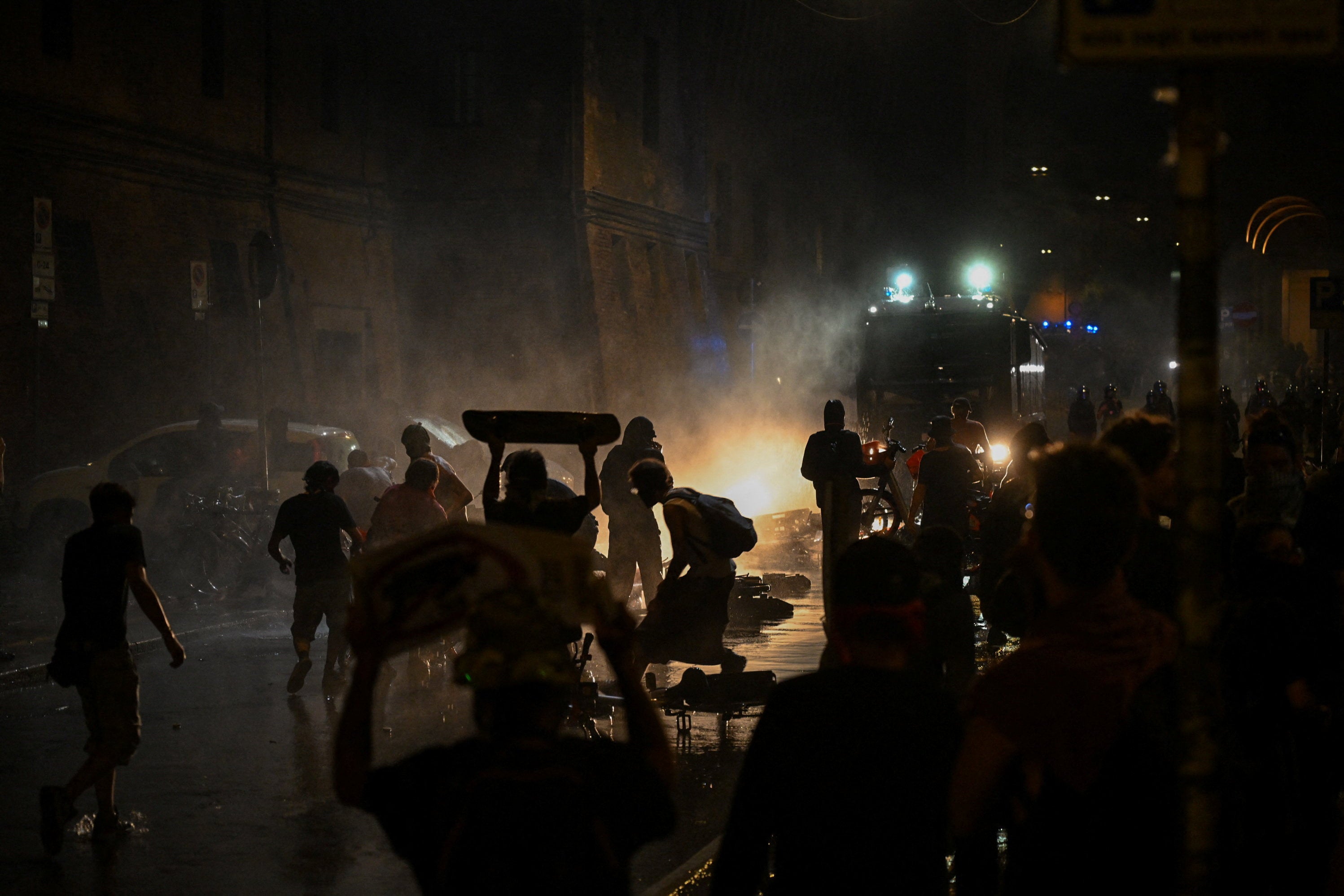 Protesters confront police amid smoke as a police vehicle moves along a street during a demonstration following the death of Abderrahim Fakir, in Bologna, Italy, July 20, 2026. (Reuters)