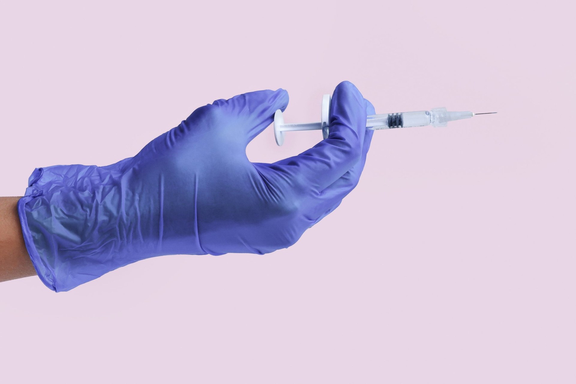 Hand of a cosmetologist doctor in gloves holding a medical syringe