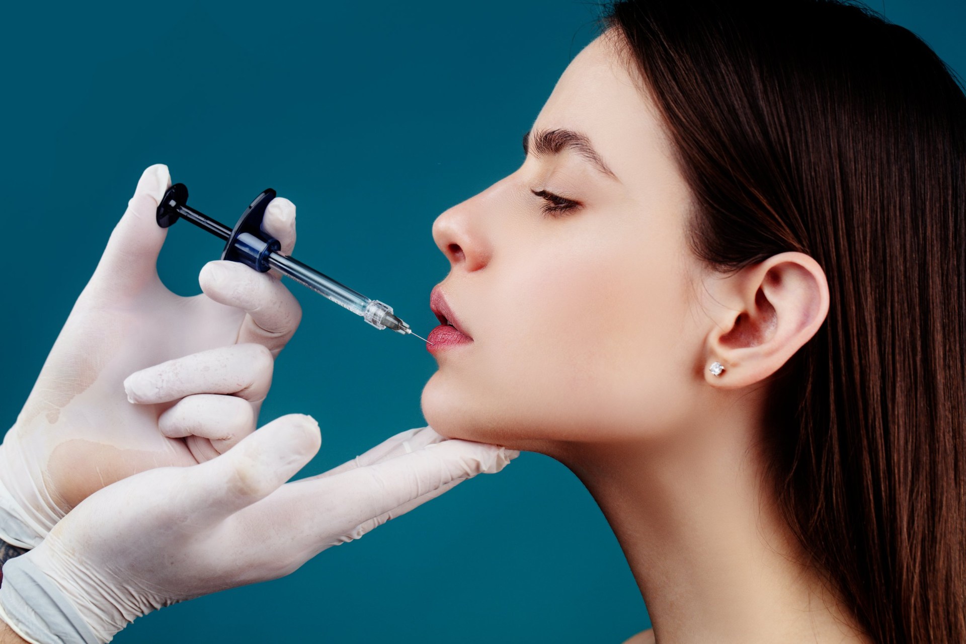 Hand of cosmetologist making injection in female lips