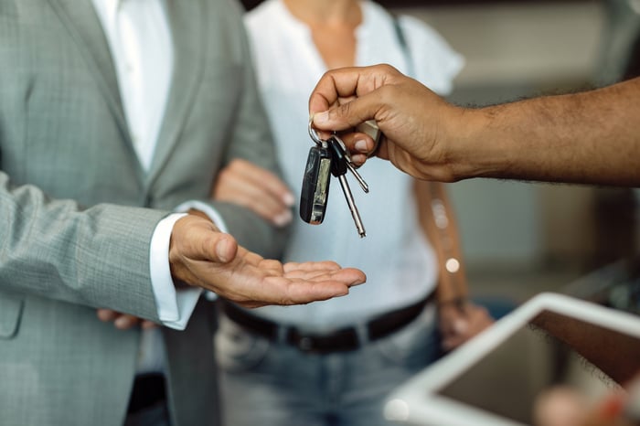 One person handing car keys to another.