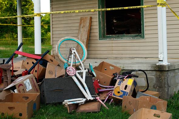 Police tape surrounds a home and debris is seen on the front lawn, where authorities say they removed 16 children and arrested four adults in Hamden, Ohio, Wednesday, July 1, 2026. (AP Photo/Carolyn Kaster)