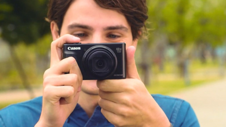 A person taking a picture with a black Canon PowerShot SX740 HS camera