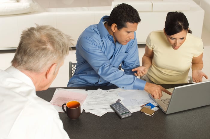 A couple reviewing financial statements on a laptop with an advisor.