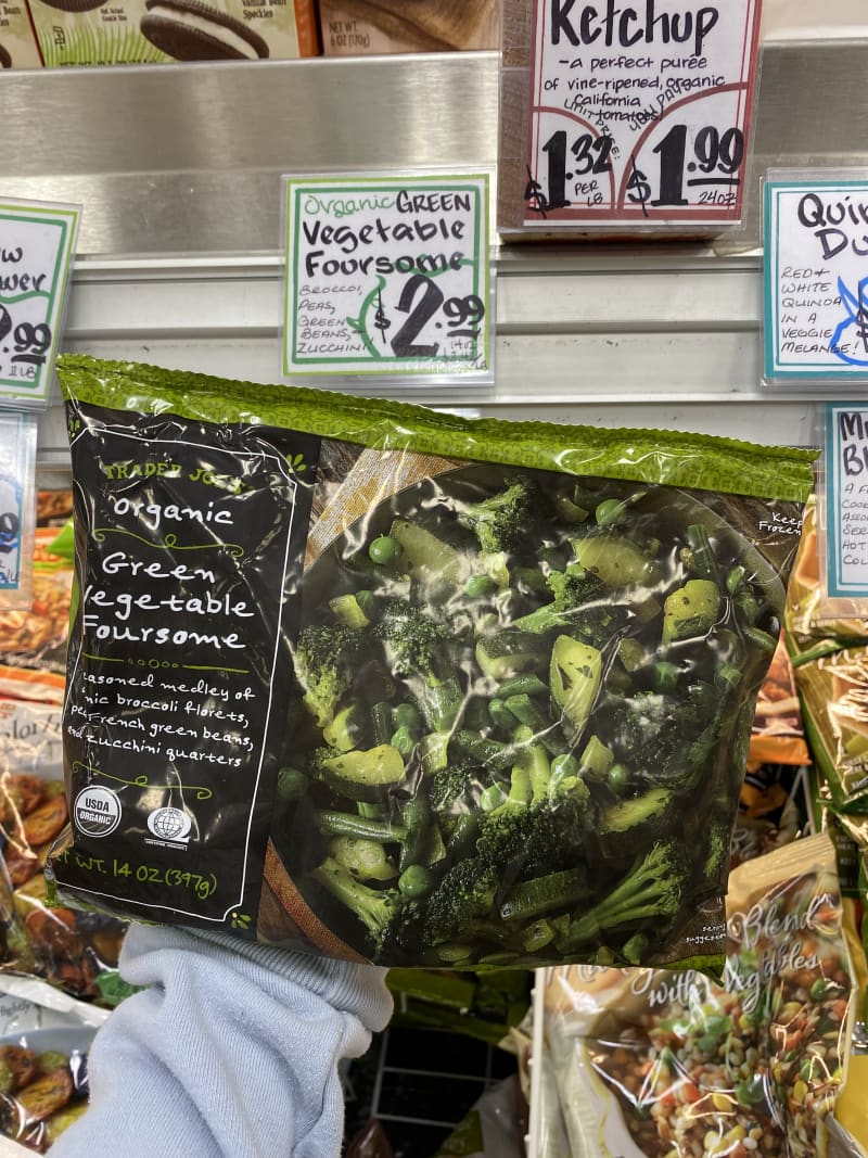 Bag of Trader Joe's Organic Green Vegetable Foursome held in front of store shelf with price tag.