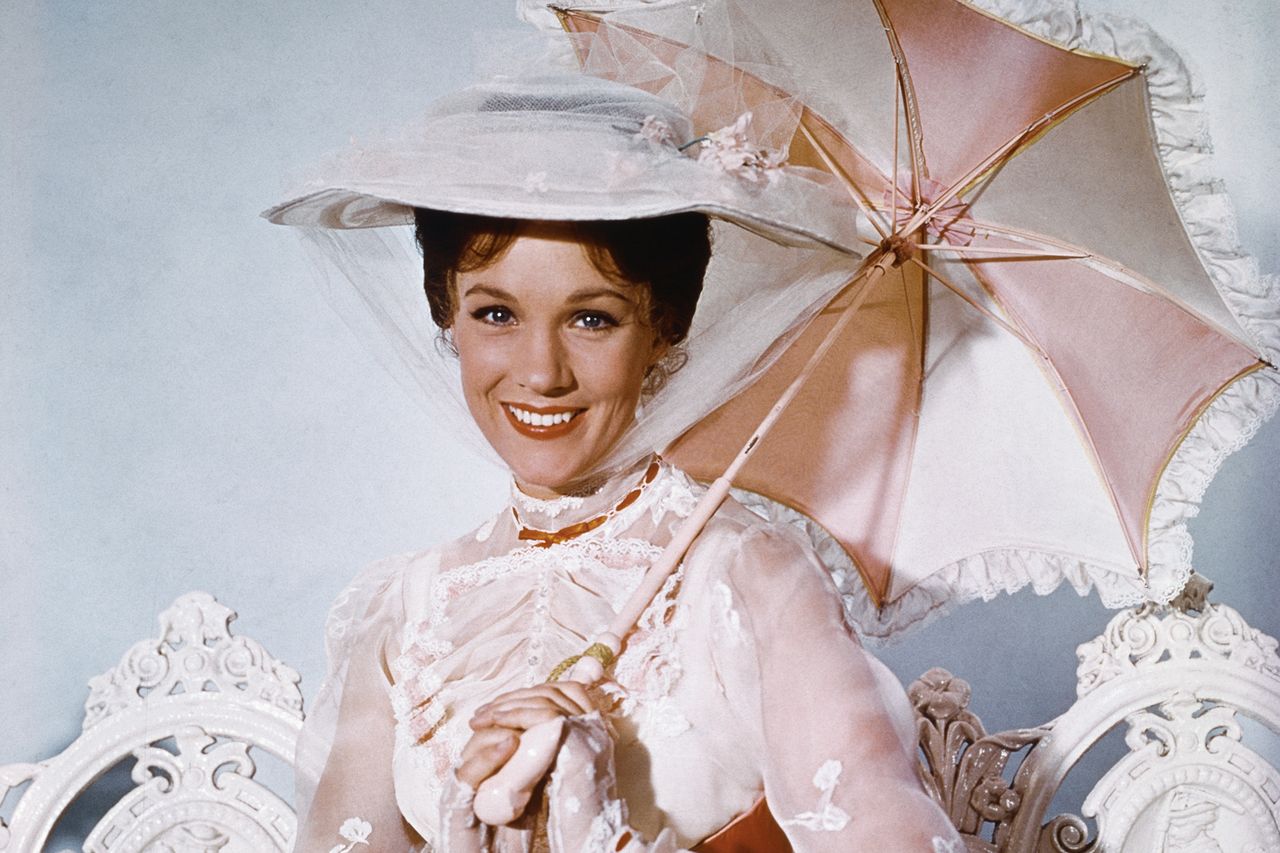 Julie Andrews holding an umbrella and dressed in periodstyle attire