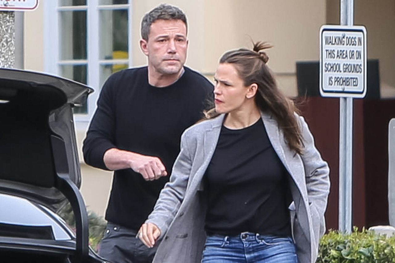 Ben Affleck and Jennifer Garner walking outdoors near an open car trunk casual clothing and serious expressions