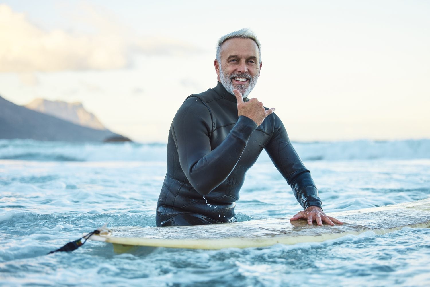 Senior man surfing in Hawaii beach, surf culture hands signal and healthy fitness in ocean nature. Friendly surfer easy greeting, retirement travel of elderly person and sea adventure lifestyle