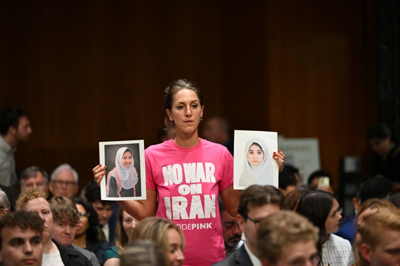 A protester against the war in Iran holds pictures before US Defense Secretary Pete Hegseth, Chairman of the Joint Chiefs of Staff Gen. Dan Caine and Secretary of Agriculture Brooke Rollins are to testify during a Senate Committee on Appropriations hearing on Capitol Hill in Washington, DC on July 21, 2026. US lawmakers are conducting a hearing to examine a review of US President Donald Trump's supplemental funding request of June 24, 2026. (Photo by Alex WROBLEWSKI / AFP via Getty Images)