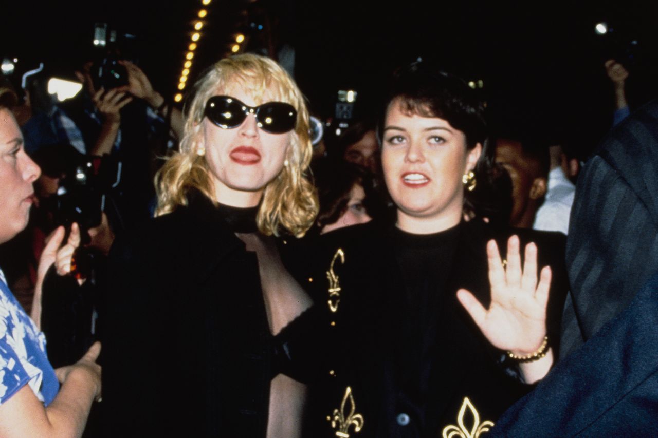 Madonna and Rosie ODonnell pose together at an event with a crowd behind them one wearing sunglasses