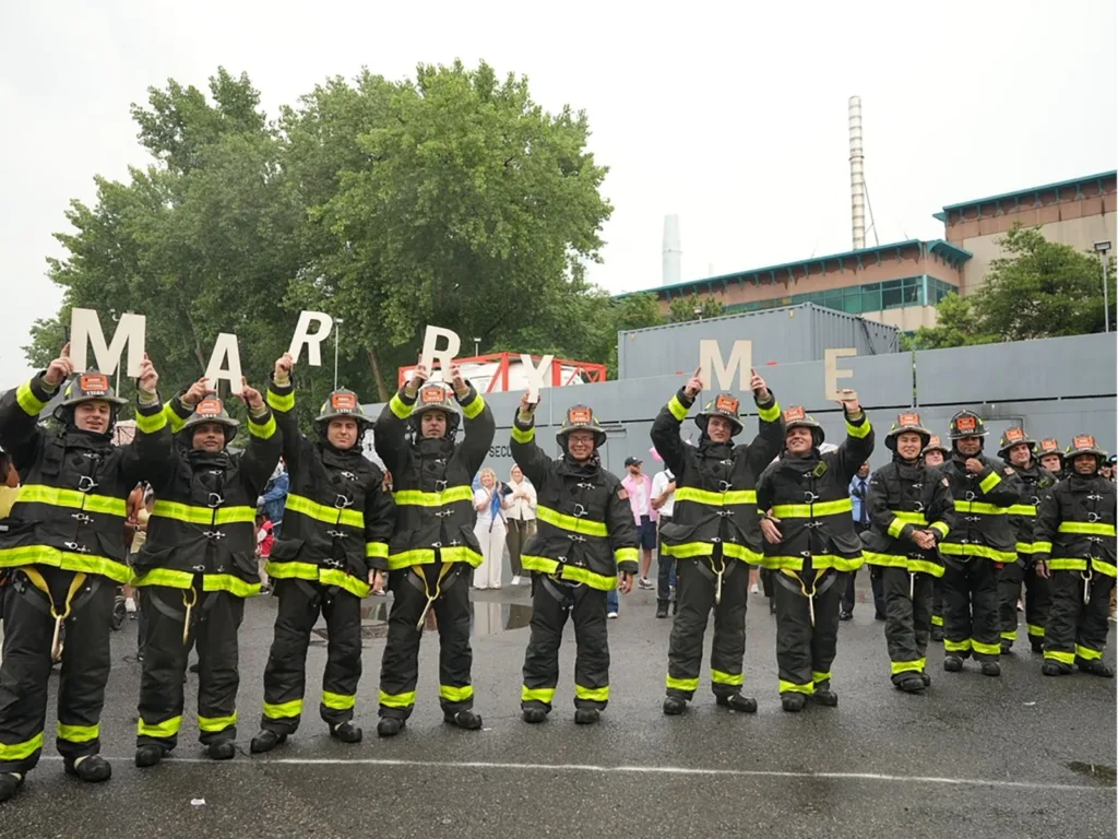 FDNY firefighters stand in a row holding letters spelling “Marry Me” during Jayson’s surprise proposal to Dasia.