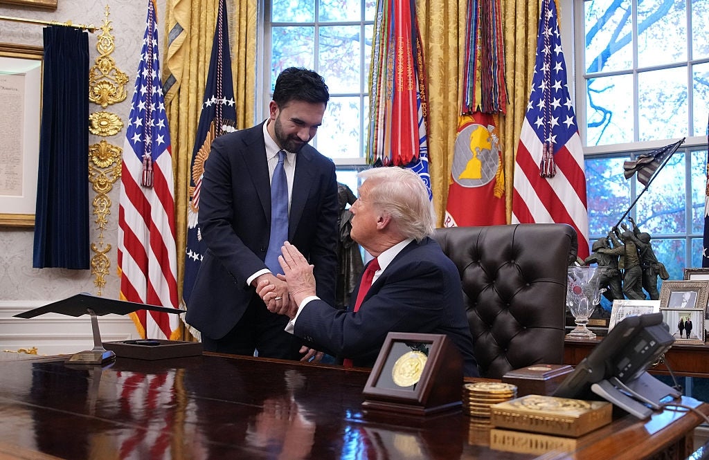 Two people shake hands in an opulent office setting with ornate decor and large windows