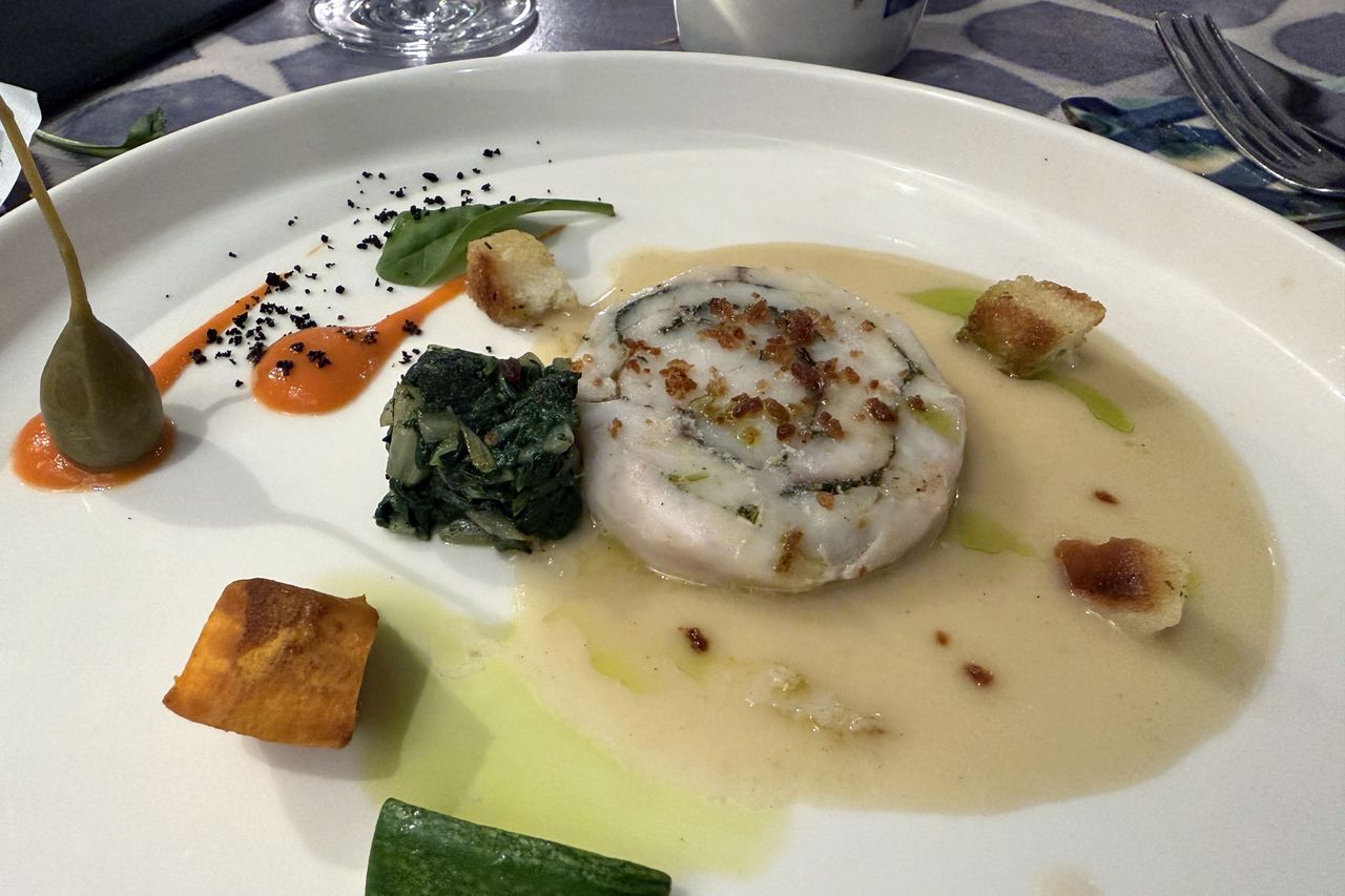 Plated gourmet dish with a rolled meat serving vegetables and sauces