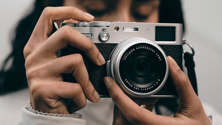 A person holding a Fujifilm X100VI camera