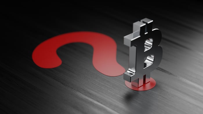A silver Bitcoin symbol atop a large, red question mark.