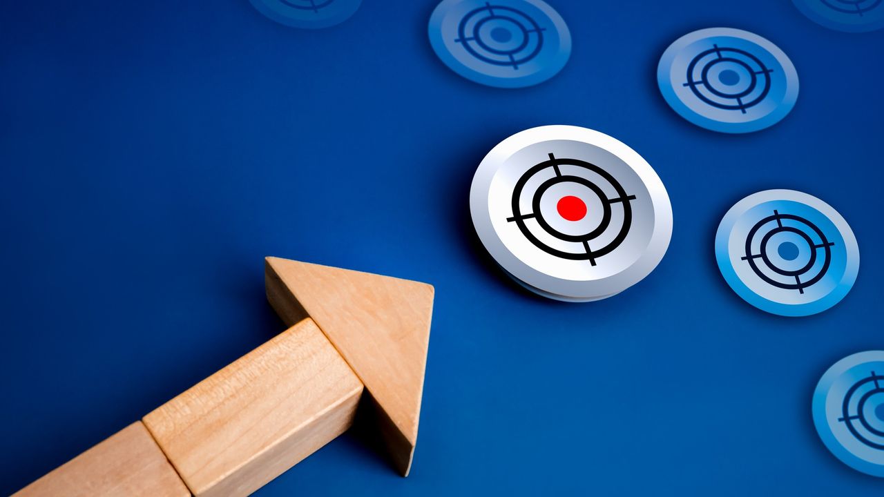 an arrow made out of wooden blocks pointing to a target icon with a red circle in the center
