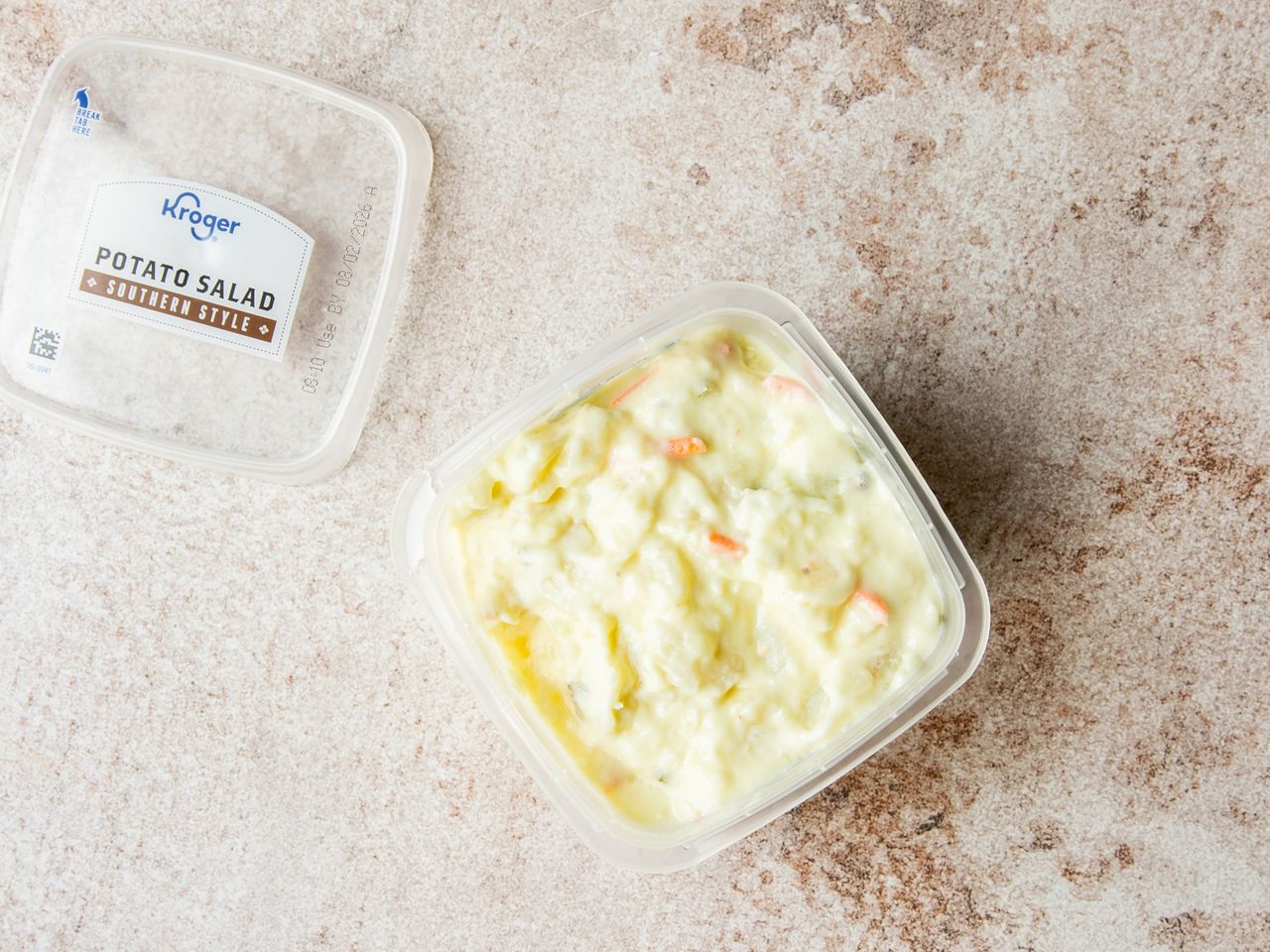 A container of Kroger Southernstyle potato salad with the lid off on a stone surface