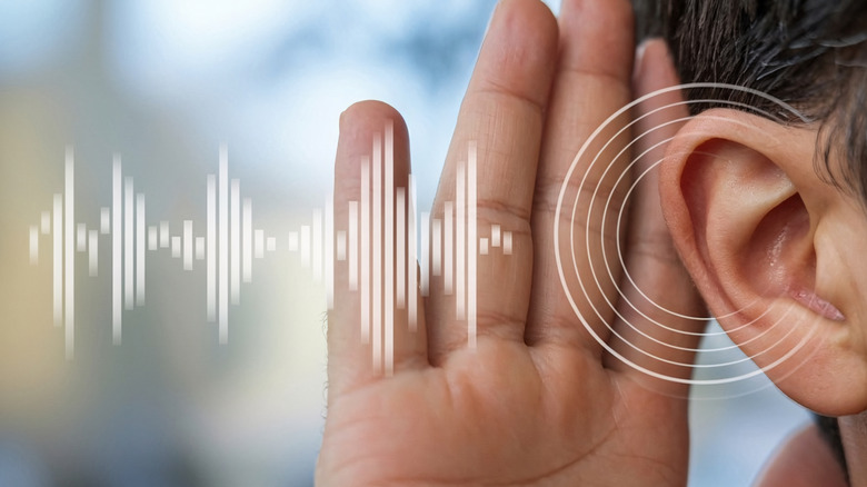 Man holding a hand to his ear with sound wave art added next to it