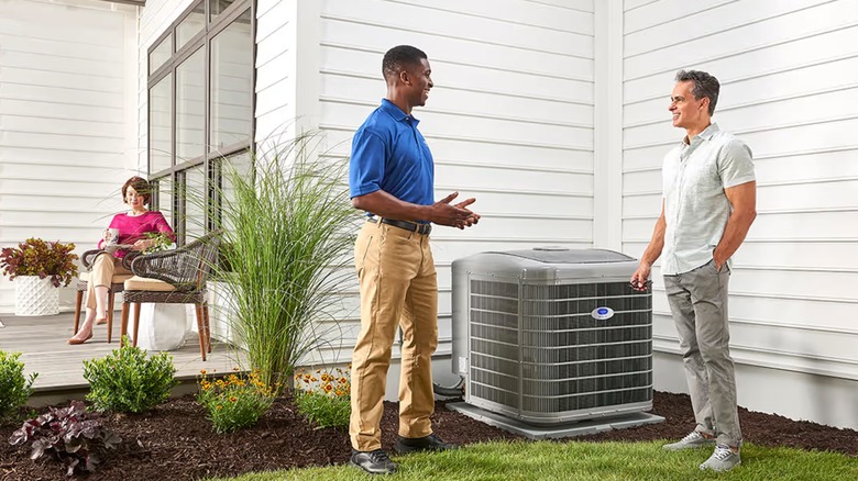 People talking beside a Carrier air conditioner.