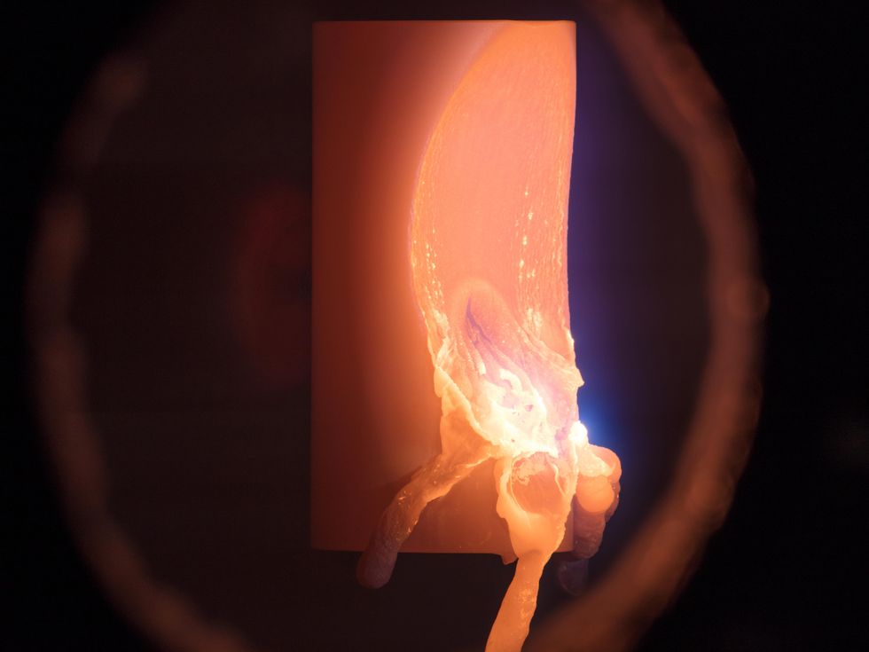 Globs of metal melting off from a 100-gram cylinder of aluminum alloy.