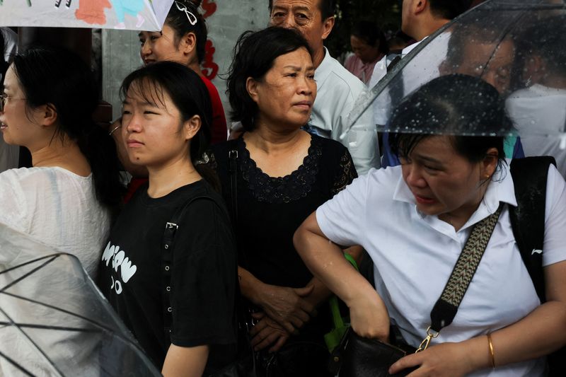 People shelter from the rain under a roof in Hangzhou