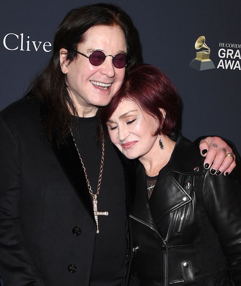 Ozzy Osbourne and Sharon Osbourne embrace at an event with a Grammy Awards backdrop
