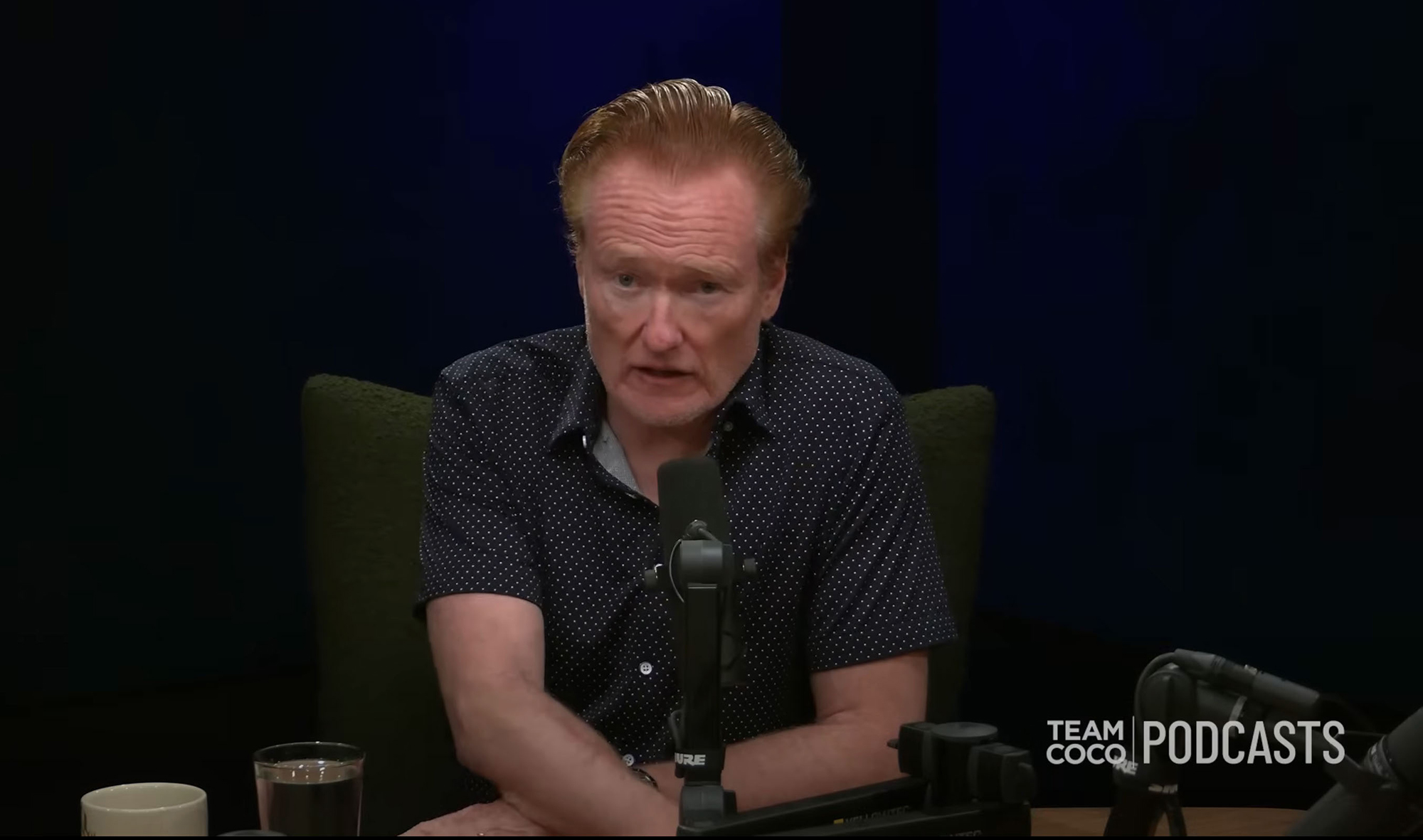 Conan O'Brien speaking into a microphone.