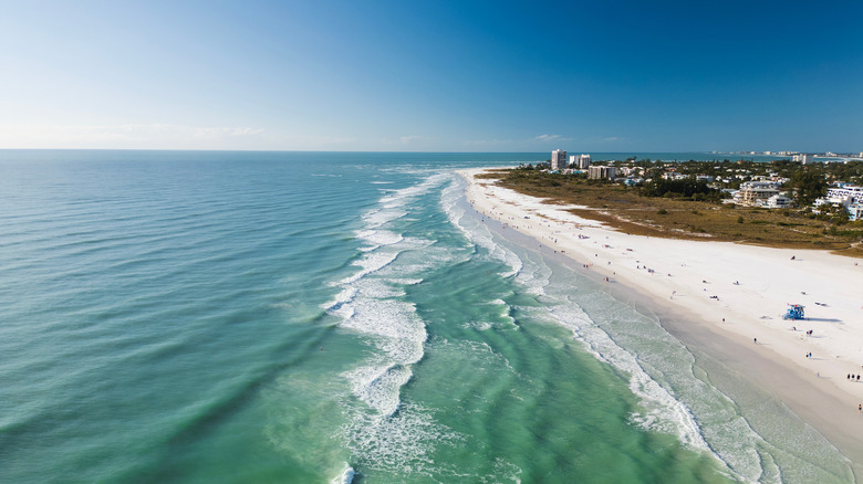 The Gulf and the white sands of Siesta Key Beach stretching into the horizon, white buildings in the distance.