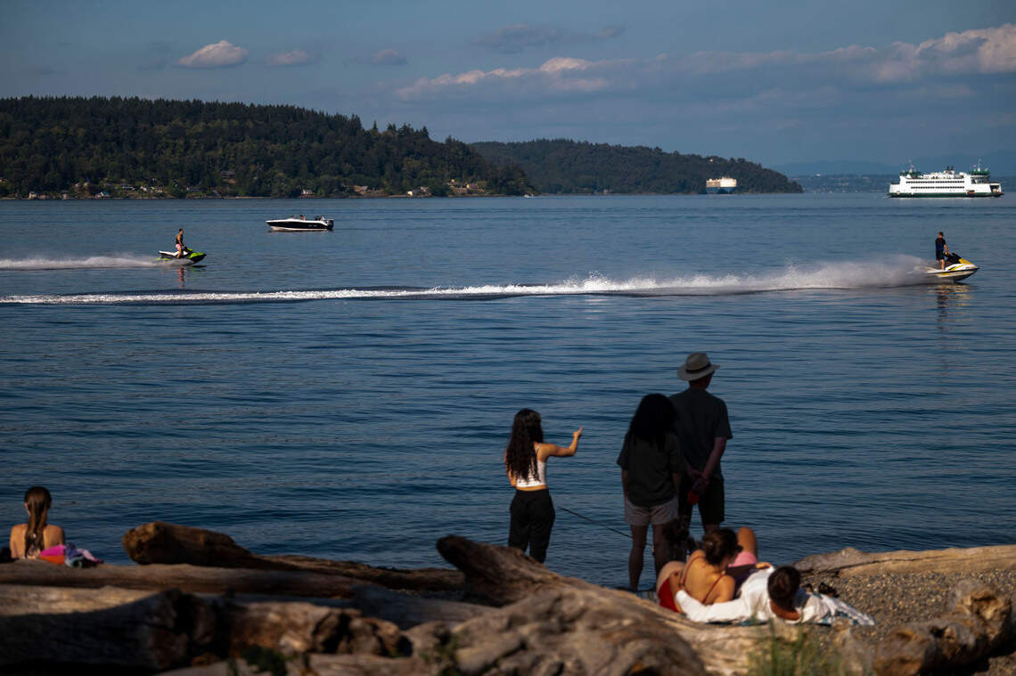 People watch as jet skiers speed past Owen Beach on Wednesday, Aug. 14, 2024, in Tacoma, Wash.