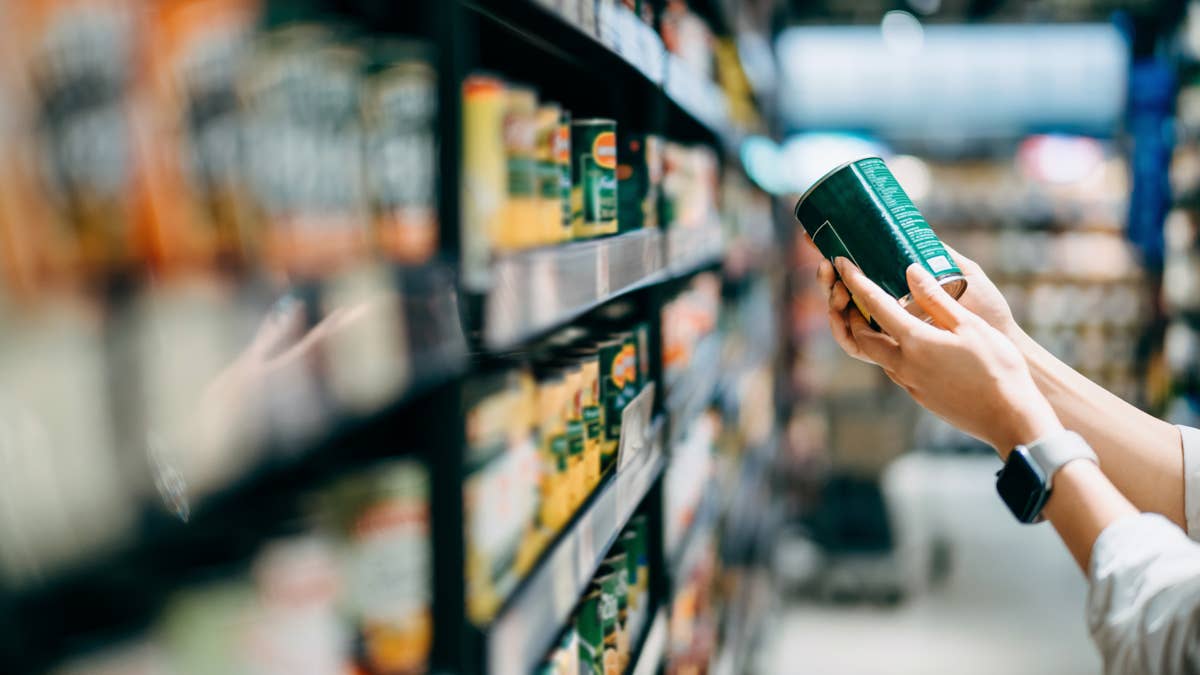 close-up-of-a-woman-grocery-shopping-in-supermarket-holding-a-tin-can-and-reading-the-nutrition-label-at-the-back