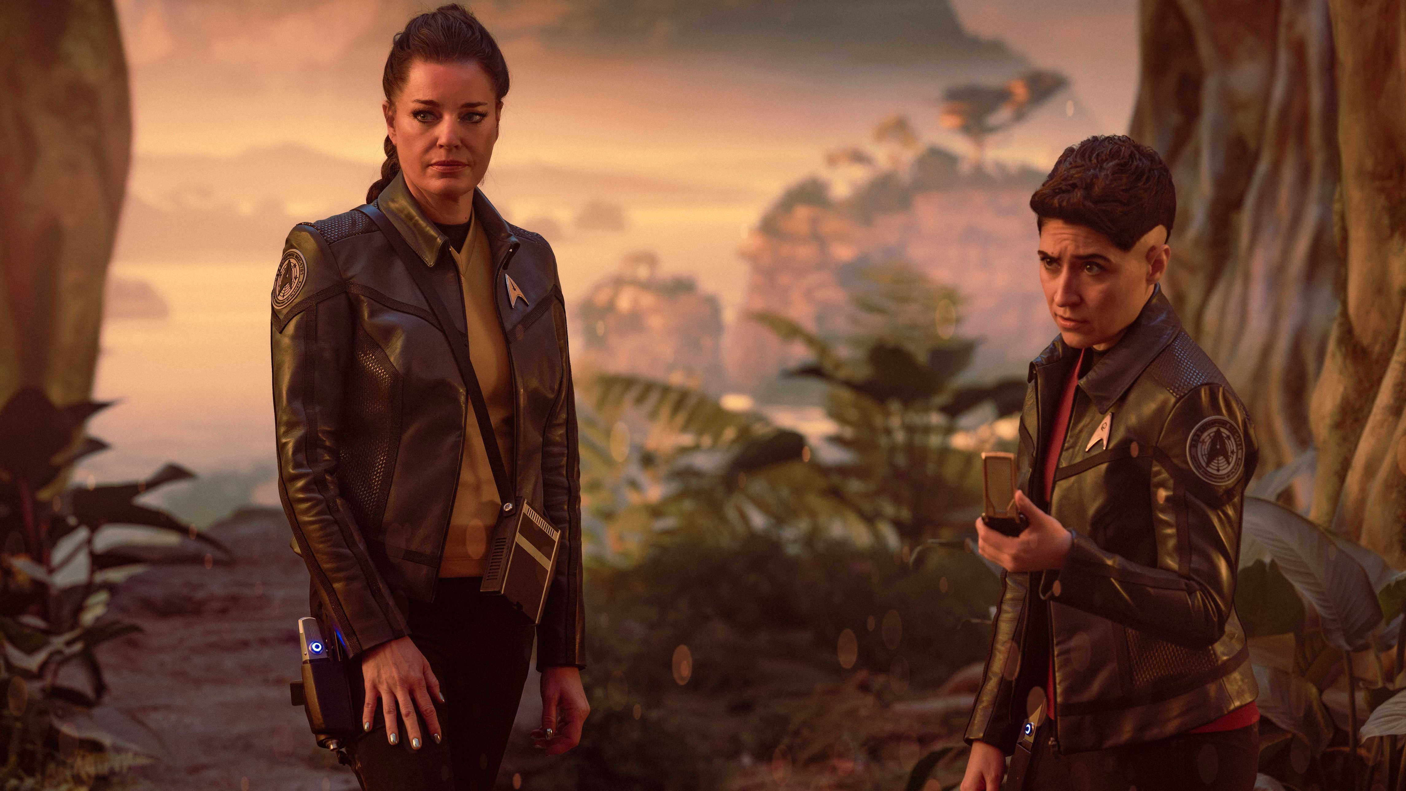 Una (Rebecca Romijn) and Erica Ortegas (Melissa Navia) stand on a prehistoric planet in Star Trek: Strange New Worlds