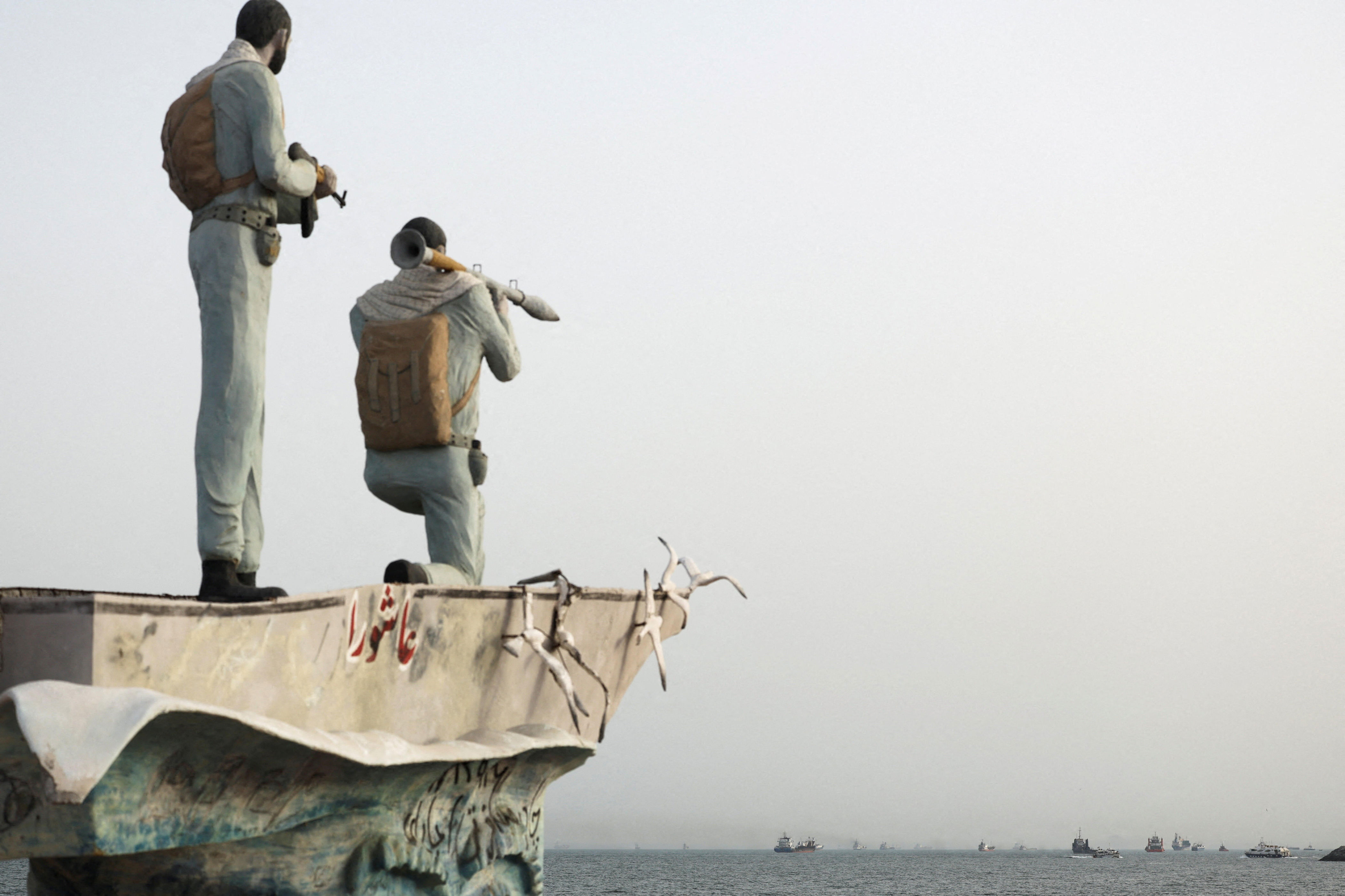 A statue of Iranian military members is seen with vessels in the Strait of Hormuz in the background, near the beach of Bandar Abbas, Iran, in a May 22, 2026 file photo. / Credit: Majid Asgaripour/WANA/REUTERS