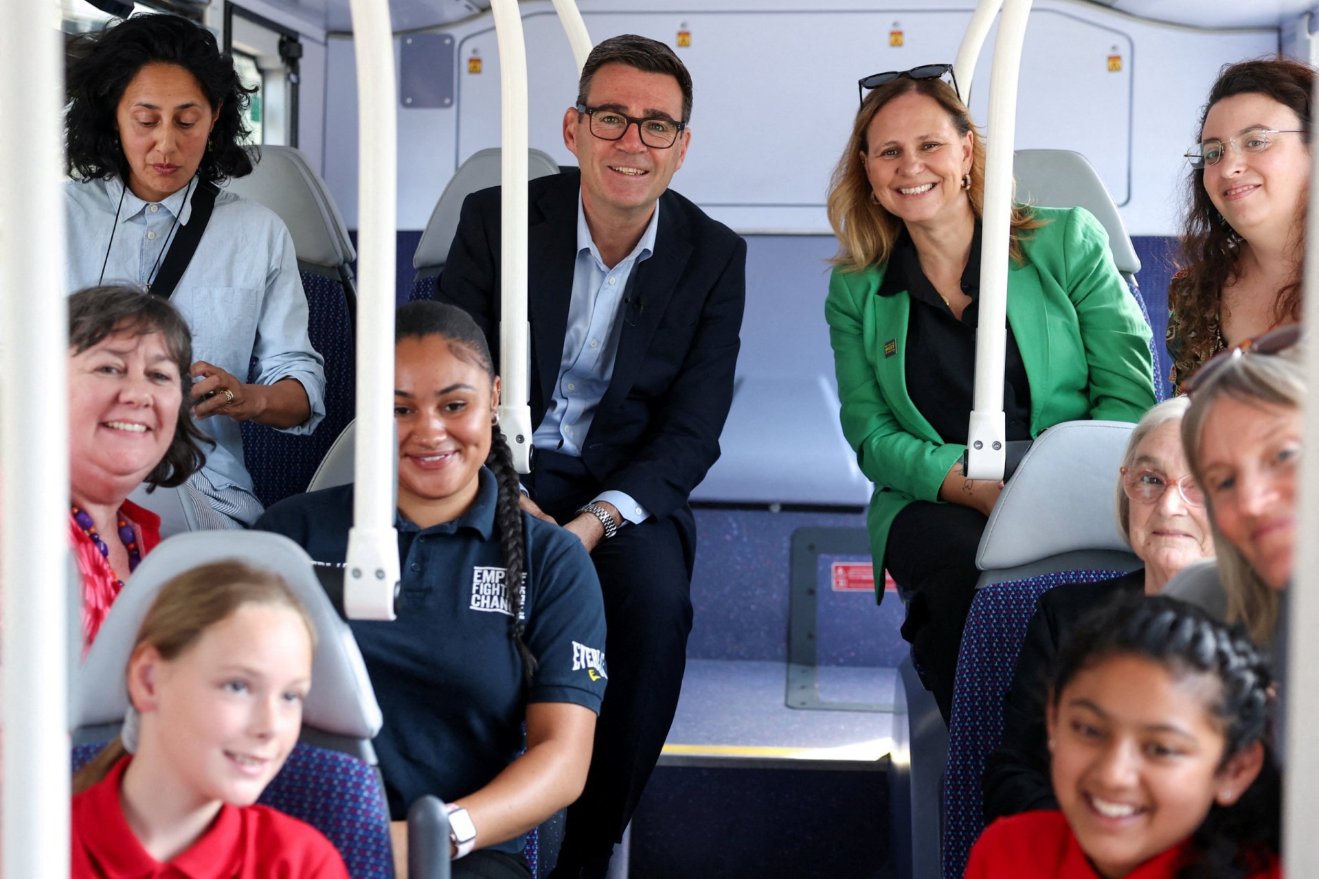 Britain's Prime Minister Andy Burnham (centre L) and Mayor for the West of England Helen Godwin (centre R) pose with locals as they take a bus ride during Burnham's visit to Bath, western England, on July 22, 2026. Burnham, who became prime minister on July 20, pledged on July 22 to ease cost-of-living pressures, unveiling a tax cut on household electricity prices and a ??2 (2.70 USD) cap on single bus fares in his first days in the job. (Photo by Toby Melville / POOL / AFP via Getty Images)