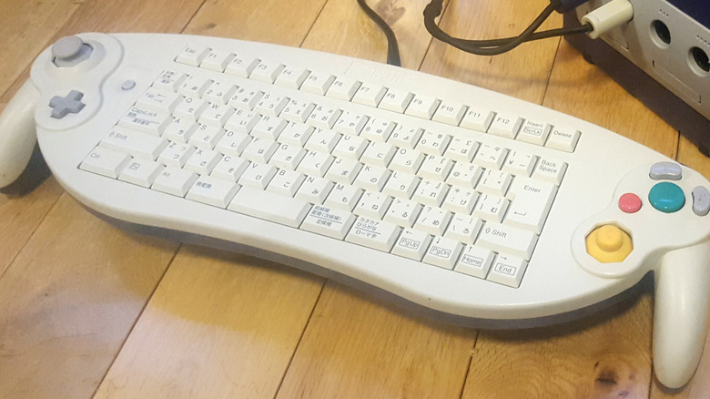 An ASCII Keyboard Controller lying on a wooden table next to a Nintendo GameCube