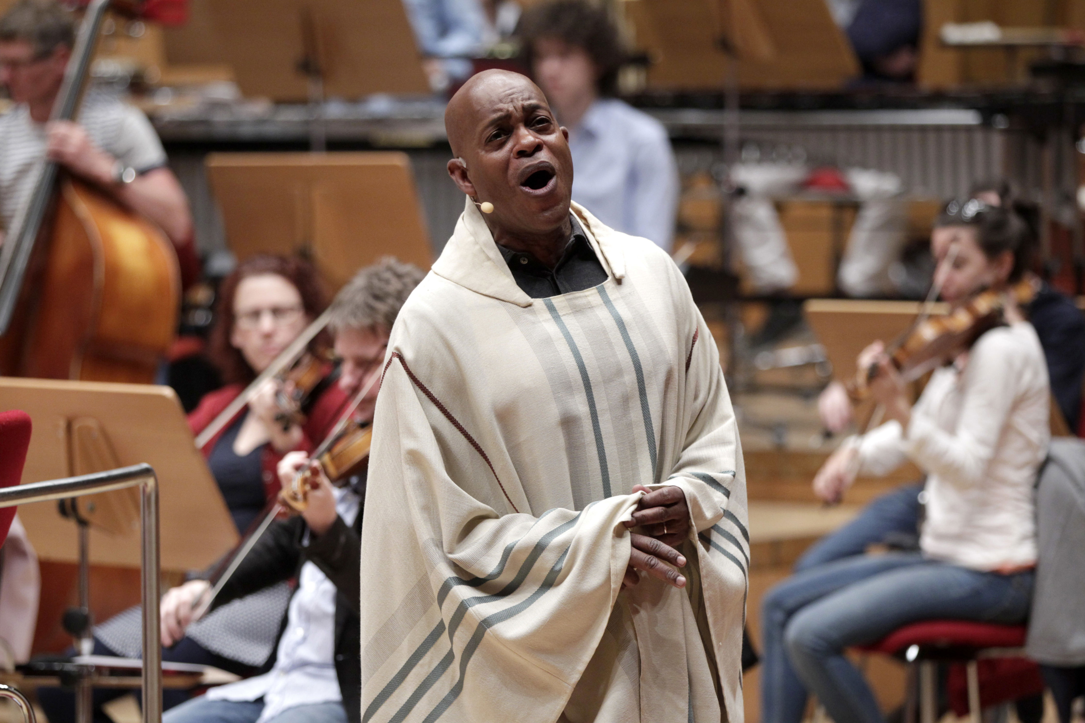 Jubilant Sykes performing in a light-colored tunic with an orchestra.